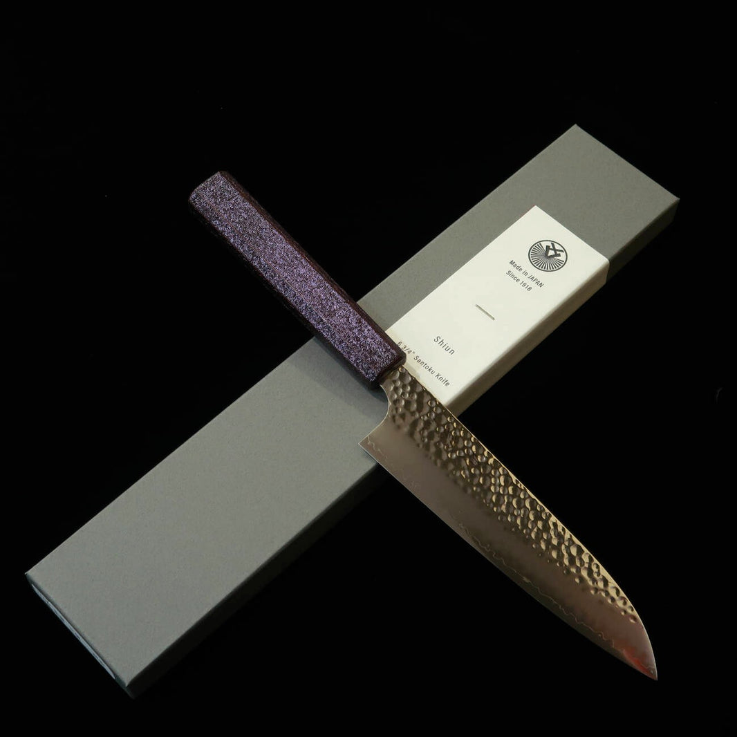 Sekikanetsugu SEIKANETSUGU Shiun SHIUN Santoku VG10, martelada, cabo octogonal em carvalho laqueado roxo “Monmurasaki” (170 mm)
